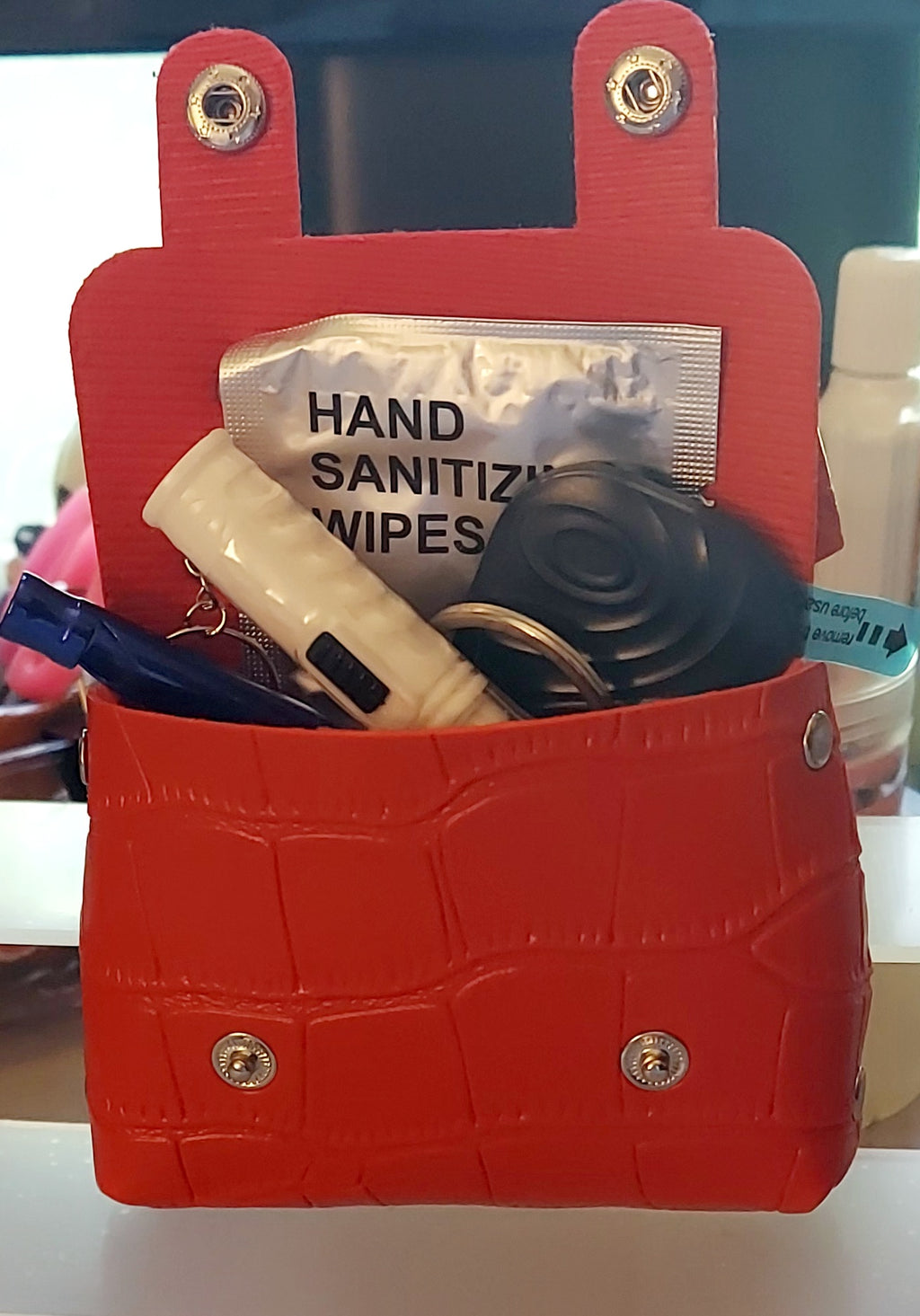 Red mini briefcase purse open showing bundle contents including hand sanitizing wipes and other items