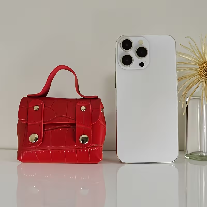 Red mini briefcase purse shown next to an iPhone for size comparison